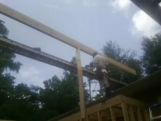 Carpenter setting a ridge beam over a new addition frame — Ice Dam Removal by Roofing Brothers in Homestead