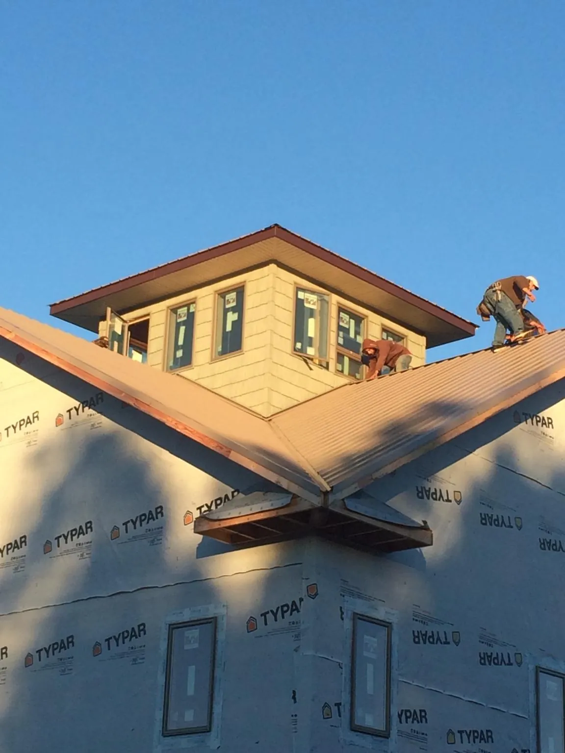 Roofers working around a rooftop cupola on a new metal roof at sunset — Roof Waterproofing in Homestead by Roofing Brothers